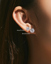 Close-up of an ear wearing two zircon solitaire earrings.